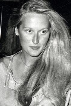 a black and white photo of a woman with long blonde hair holding a cell phone