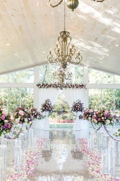 an indoor wedding venue with floral arrangements and chandelier hanging from the rafters