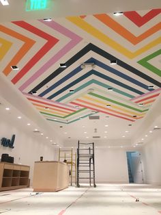 an empty room with multicolored ceiling tiles on the ceiling and ladders in front of it