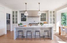 a large kitchen with white cabinets and marble counter tops, along with bar stools