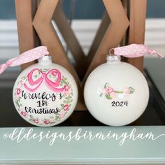 two personalized christmas ornament ornaments sitting on top of a wooden chair with pink ribbon