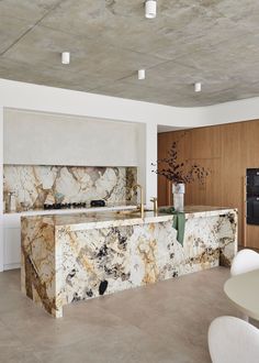 a kitchen with marble counter tops and white chairs