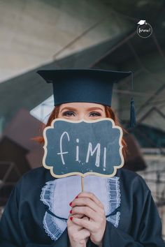 a woman wearing a graduation cap and gown holding a chalkboard with the word fim written on it