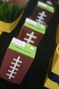 paper footballs are lined up on a table with grass in the middle and yellow tape around them