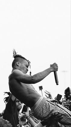 a shirtless man holding a baseball bat in his right hand and people behind him