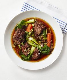 a white bowl filled with meat and vegetables on top of a blue and white towel