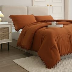 a bed with an orange comforter and pillows