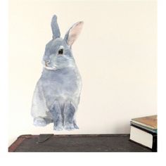 a painting of a rabbit sitting on top of an old trunk next to a book