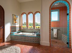 an ornate bathroom with blue and red tiles on the walls, arched windows, and a large jacuzzi tub