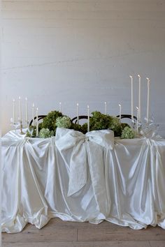 the table is covered with white cloth and has candles on it, as well as flowers