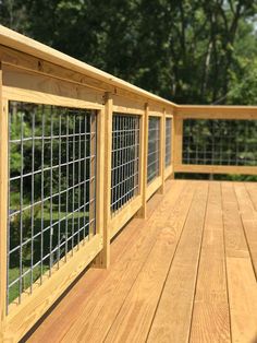 a wooden deck with metal railings and trees in the background