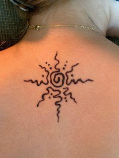 the back of a woman's neck with an intricate tattoo design on her left shoulder