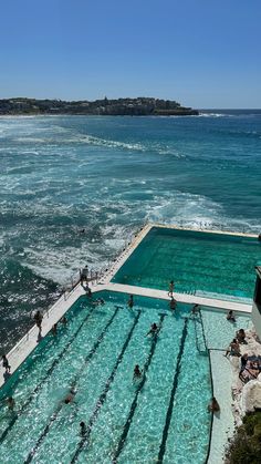 people are swimming in an outdoor pool next to the ocean