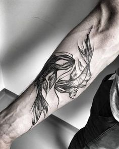 a black and white photo of a person's arm with a fish tattoo on it