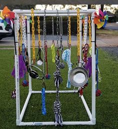 a rack with many different items hanging from it's sides on the grass in front of a park