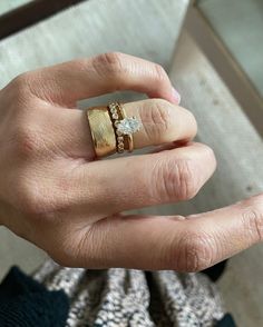 a woman's hand with two gold rings on top of her finger and the other ring