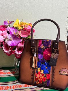 Beautiful hand-made leather embroidered tote. This handcrafted Leather Embroidered Tote was made by Mexican Artisans. The embroidered design is full of vibrant colors. Artisan Hand Painted Brown Bags, Rectangular Leather Bag With Floral Embroidery, Leather Bag With Floral Embroidery And Rectangular Shape, Bohemian Multicolor Leather Satchel, Embroidered Brown Tote Satchel, Multicolor Hand Tooled Travel Bags, Brown Embroidered Tote Satchel, Leather Bag With Multicolor Embroidery For Everyday Use, Bohemian Leather Shoulder Bag With Embroidery