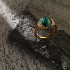 Description Inspired by the beautifully patterned Malachite gemstone, the earliest ore of copper, Tamra is eccentric, contemporary, and distinctively classy. Handcrafted on 925 hallmark silver and gold finish. This collection is curated for everyday luxury. This finger ring features a round malachite charm at the center. The side of the charm is highlighted with two lines of CZ stones to add extra glam. Striking ring to style with Paksha's unmatched delicate jewelry. Product Information Material Elegant Emerald Dome Ring, Elegant Round Emerald Dome Ring, Gold Plated Crystal Ring With Gemstone, Elegant Gold Emerald Ring With Round Stone, Elegant Malachite Gemstone Ring, Gold Emerald Ring With Gemstone Accents, Luxury Malachite Jewelry, Luxury Round Emerald Ring With Stone Setting, Luxury Round Malachite Jewelry