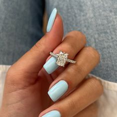 a woman's hand with light blue nails and a diamond ring on her finger