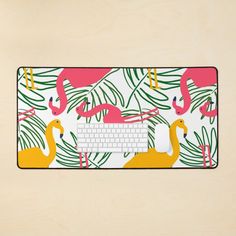 a computer mouse pad with pink flamingos and palm leaves on the front, along with a keyboard