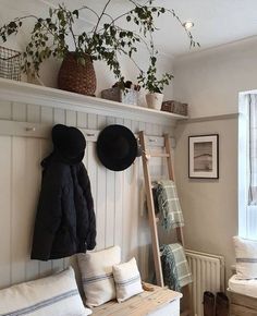 a coat rack with hats on top of it next to a bench and window sill