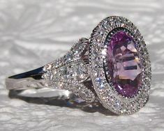 A beautiful and elaborate white gold engagement ring, featuring a sparkly untreated purplish pink sapphire, set in my Iris mount with a diamond halo. The center stone in a beautiful Ceylon sapphire with a violetish pink color. The oval sapphire weighs 2.48 carats and measures 10x7.4mm. It is eye-clean and completely untreated and comes with a GIA report. A great one-of-a-kind gem for an engagement ring or any special occasion! The sapphire is set in a beautiful and elegant 14K white gold IRIS ri Elegant Silver Pink Sapphire Ring, Elegant Silver Ring With Pink Sapphire, Oval Purple Sapphire Ring With Diamond, Oval Purple Platinum Rings, Purple Oval Sapphire Ring, Brilliant Cut, Purple Oval Sapphire Ring With Brilliant Cut, Purple Brilliant Cut Oval Sapphire Ring, Purple Diamond Engagement Ring, Purple Diamond Ring