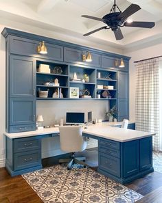 a home office with blue cabinets and a ceiling fan