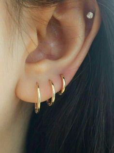 a close up of a person wearing gold ear cuffs with diamond studs on them