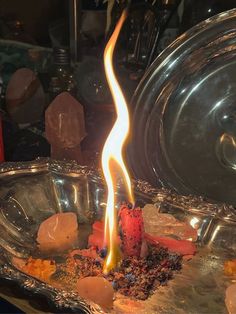 a candle that is sitting in some kind of metal bowl with rocks and stones around it