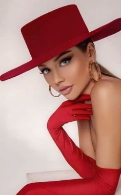 a woman in a red dress and hat posing for the camera with her hands on her hips