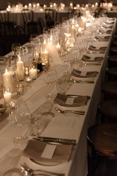 a long table is set with wine glasses and candles