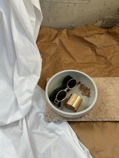 a white bowl with sunglasses and some gold flakes in it on a brown sheet