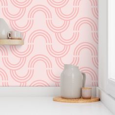 a pink wallpaper with white vases and cups on the counter in front of it