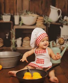 a baby sitting on the floor in front of a pan with lemons and oranges