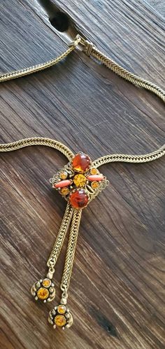 This stunning necklace in the classic Selro style features gold-tone metal set with stones in shades of gold and orange. This statment piece is on a heavy chain with snap-lock clasp. It is adjustable with the main decorative pendant slide. The ends of the chain are decorated with bezel set rhinstones. This is an absolutely stunning piece! This is a vintage piece. The piece photographed is the item you will receive. Please see photos for details and condition Retro Adjustable Gold Necklace, Adjustable Retro Gold Necklace, Adjustable Gold Jeweled Necklaces, Elegant Orange Chain Jewelry, Elegant Orange Jewelry With Chain, Vintage Gold Jeweled Rhinestone Necklace, Retro Gold Jewelry With Adjustable Chain, Vintage Gold Rhinestone Necklace, Vintage Orange Jewelry For Party