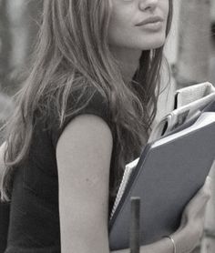 black and white photograph of a woman holding a book in her hands while looking off into the distance