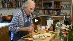 an older man in the kitchen preparing food on a cutting board with knife and fork