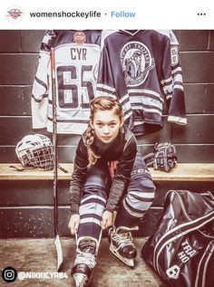 a woman sitting on the ground next to hockey gear