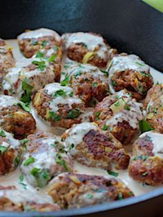 a pan filled with meatballs covered in white sauce