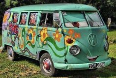 an old vw bus with flowers painted on it's side parked in the grass