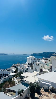 an aerial view of white buildings and the ocean in the background, with blue sky