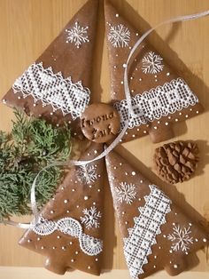 three pieces of gingerbread decorated with white and brown icing on top of a wooden table