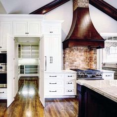 an open kitchen with white cabinets and wood flooring is pictured in this image, there are two ovens on either side of the stove