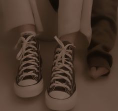 a person with their legs crossed wearing brown and white sneakers