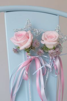 two pink roses are sitting on top of a blue chair with ribbons and bows around it