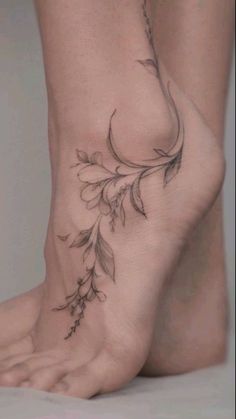 a woman's foot with flowers and leaves on the bottom part of her leg