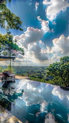 the sky is reflected in the pool as clouds hover over the trees and land