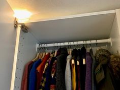 a closet with clothes hanging from the ceiling and lights above it, all in different colors