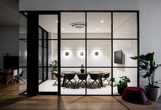 an office meeting room with glass walls and plants in the corner, along with chairs