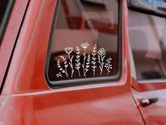 a red car with flowers on the side window and sticker in front of it